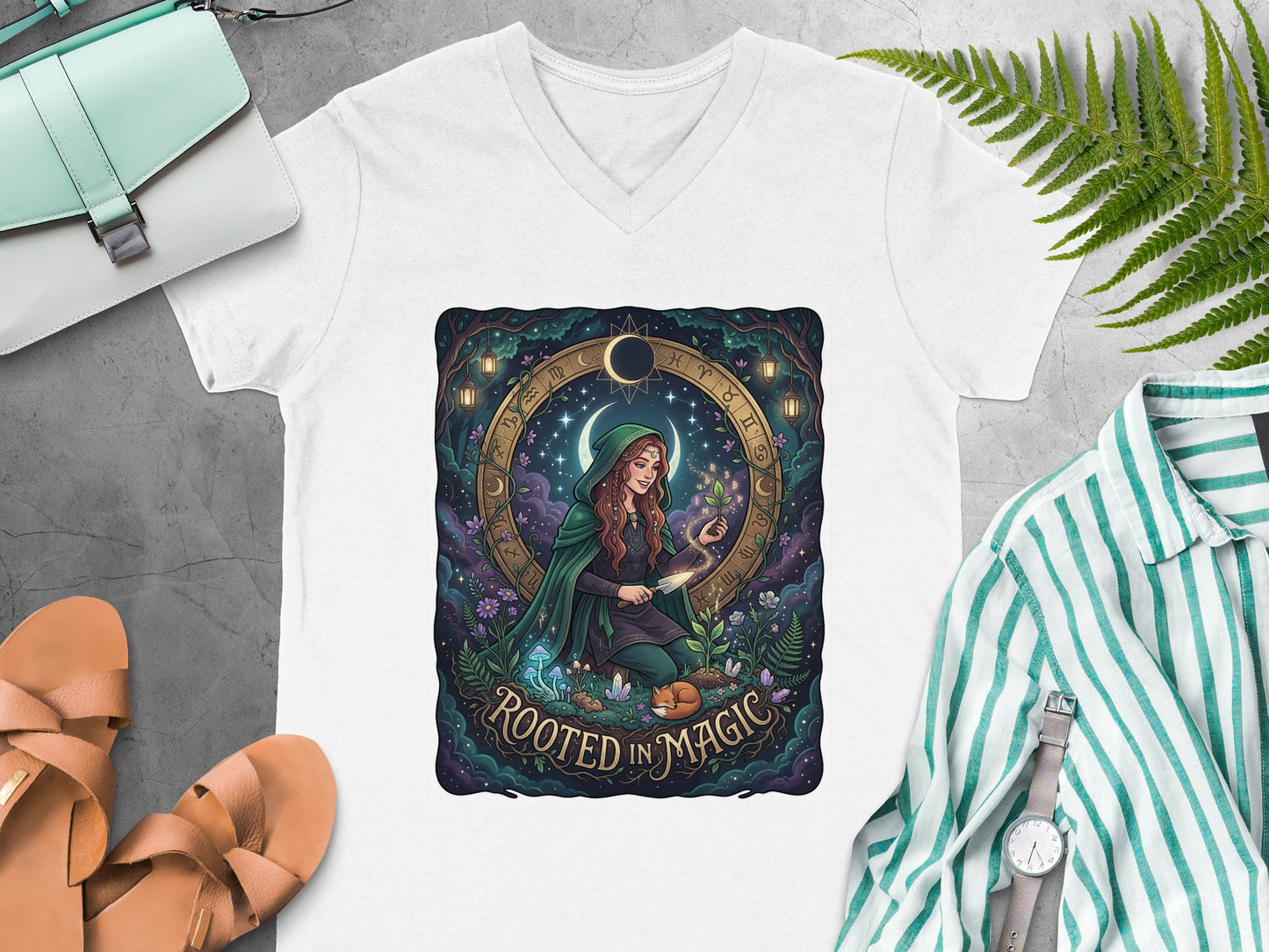 White v-neck t-shirt with "Rooted in Magic" design featuring a witch and celestial symbols.