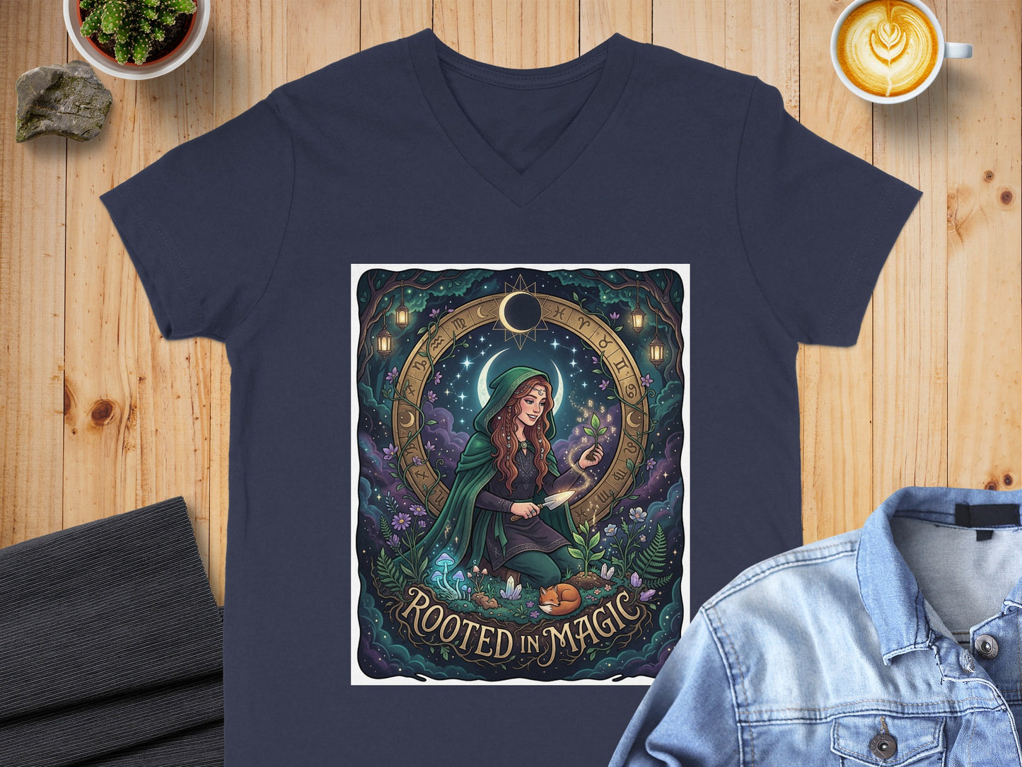 Woman in green hooded cloak with zodiac symbols and text "Rooted In Magic".