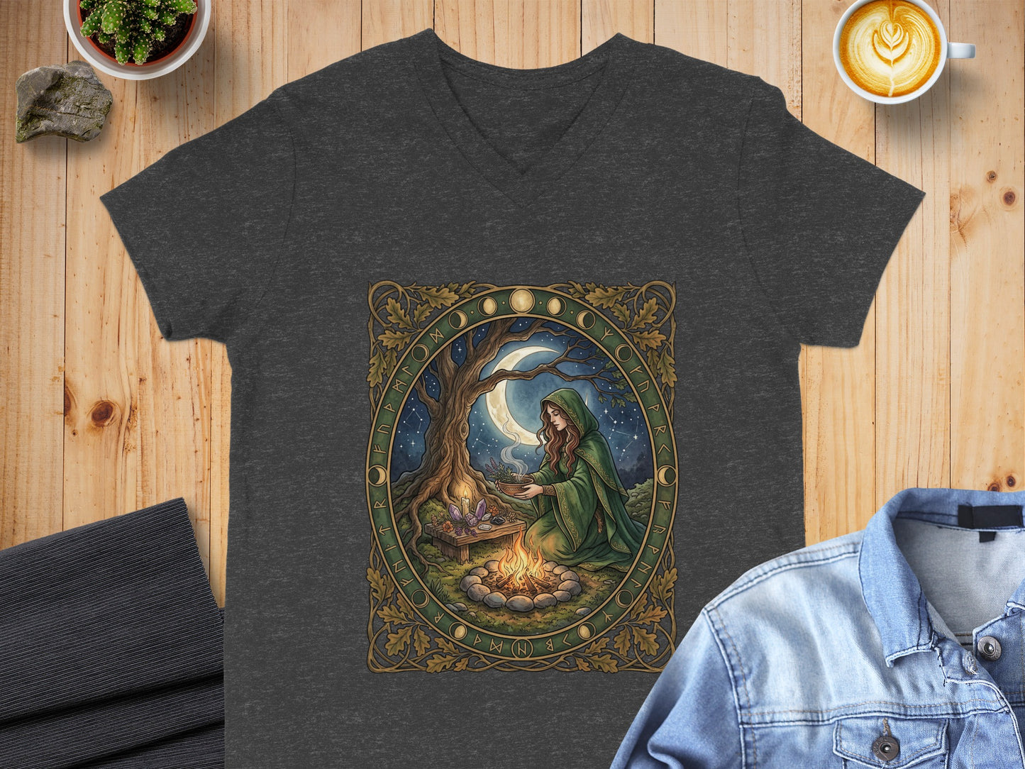 Dark t-shirt with a woman in a green cloak by a bonfire under a starry sky.