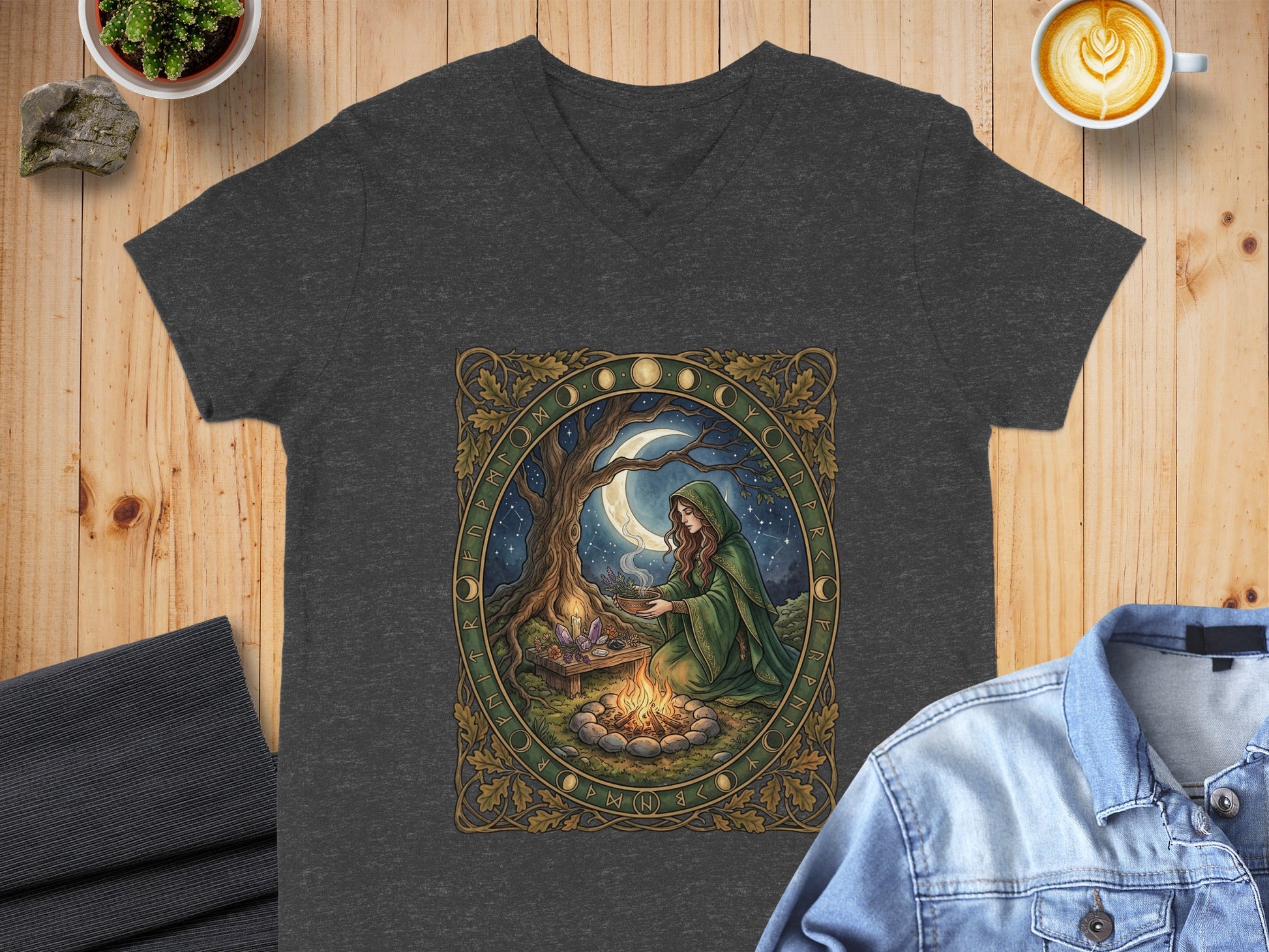 Dark t-shirt with a woman in a green cloak by a bonfire under a starry sky.